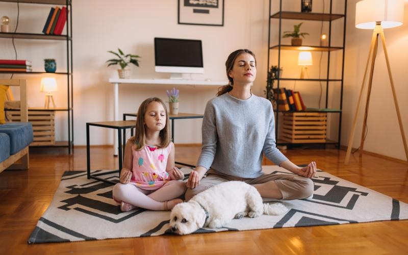 a person and a girl sitting on a rug with a dog