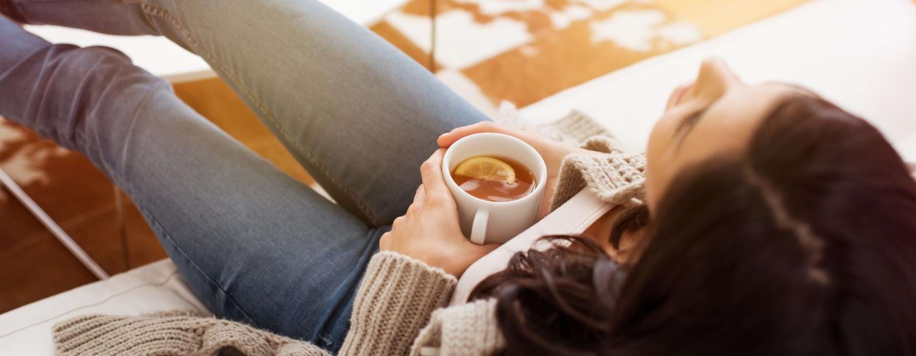 a person lying on a bed with a cup of coffee